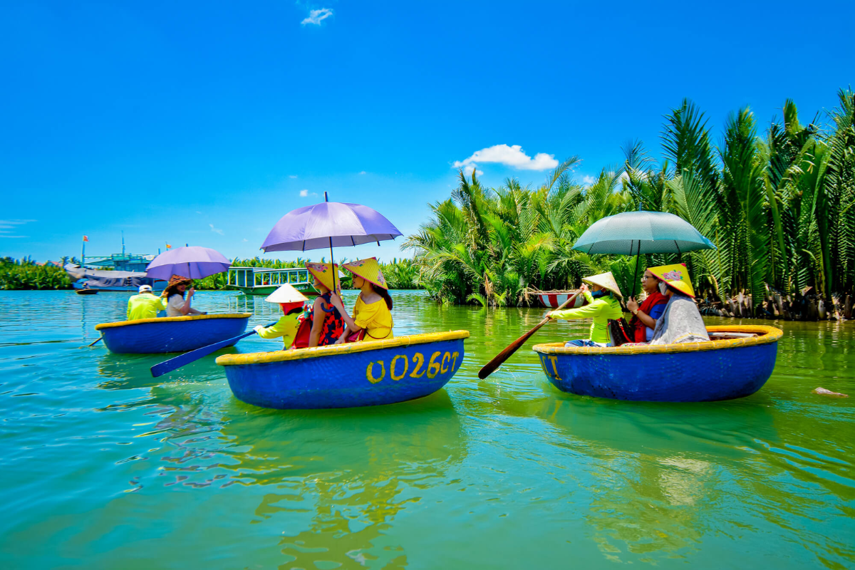 Tourist paddling through the Cam Thanh Coconut Village in a traditional basket boat